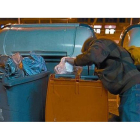Una persona busca comida en un contenedor de desechos orgánicos.