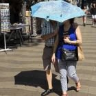 Ola de calor en Barcelona. Una pareja se protege del sol con un paraguas en las Ramblas.