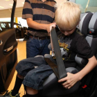 Un niño con una silla reglamentaria se ajusta el cinturón de seguridad.