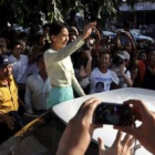 Suu Kyi saluda a sus seguidores al abandonar las oficinas de su partido.