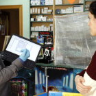 José Carlos, gerente de Asga Informática, atiende a una clienta, protegido con guantes y mascarilla, en su tienda de la calle Covadonga. MARCIANO PÉREZ