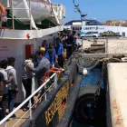 Varios inmigrantes rescatados en alta mar se disponen a desembarcar en el puerto italiano de Lampedusa.