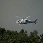Un helicóptero gana altura tras arrojar su carga de agua.