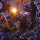 Un grupo de manifestantes refuerzan una barricada frente a los antidisturbios, en la plaza de la Independencia de Kiev.