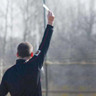 Un árbitro muestra una tarjeta amarilla a un jugador durante un lance del partido.