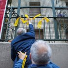 Dos de los miembros de los Grupos de Defensa y Resistencia retiran los lazos amarillos. ENRIC FONTCUBERTA