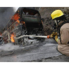 Un bombero trata de extinguir el fuego de un autobús en llamas.