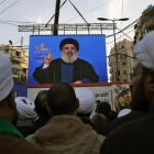 Seguidores de Hizbulá escuchan a su líder que aparece en una pantalla gigante en una manifestación en Beirut.