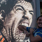 Un aficionado bromea ante un cartel publicitario protagonizado por Luis Suárez, en Copacabana.