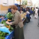 Una mujer examina las lechugas en un puesto del mercado con el fin de elegir la mejor