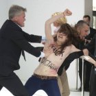 Personal de seguridad detienen a una activista de Femen que irrumpió en topless durante la visita del presidente ruso.