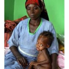 Una mujer espera junto a su hijo en un campo de refugiados