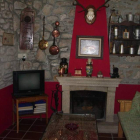 Salón con chimenea y fachada dela casa rural Los Pinos de Babia, en Piedrafitade Babia.