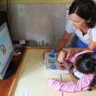 Una asistente instruye a una niña enferma de parálisis cerebral en el uso de nuevas tecnologías en las instalaciones de San Cayetano.