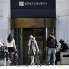 Varios periodistas esperan a las puertas de la sede del Banco de Madrid.