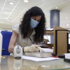 Una funcionaria del servicio de préstamo con mascarilla en la biblioteca pública. FERNANDO OTERO