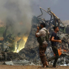 Un grupo de hombres inspecciona los restos del helicóptero ruso que los rebeldes sirios han derribado este lunes en la provincia de Idleb
