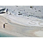 SOS escrito en la arena de playa por  Linus y Sabina Jack.