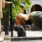 Un hombre se refresca en una fuente en Córdoba. SALAS