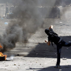 Un palestino lanza piedras contra la policía en una protesta.