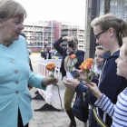 La cancillera Merkel, recibida con ramos de flores de niños a su llegada al Parlamento regional de Dusseldorf, con motivo del 70 aniversario de la CDU, el 30 de septiembre.