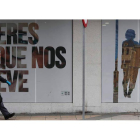 Un hombre paseando ayer ante un establecimiento cerrado en León.