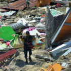Un hombre carga objetos personales entre los escombros de un edificio derrumbado por el terremoto, en la ciudad indonesia de Palu.