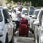 Una viajera pasa ayer entre dos filas de taxis en huelga. RAÚL CARO