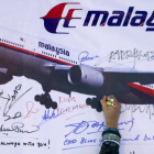 Una mujer escribe un mensaje de solidaridad con los pasajeros del vuelo desaparecido de Malaysia Airlines en Kuala Lumpur en el 2014.