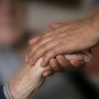 Un enfermo de Alzhéimer da la mano a un familiar.