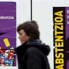 Una mujer pasa ante algunos de los carteles pidiendo la abstención en las elecciones vascas.