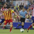 Arda Turan agarra al argentino Leo Messi durante el partido de ida de la Supercopa.