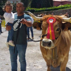 El joven ganadero, con su hija en brazos, junto a una de sus vacas en un reciente concurso. ARAUJO