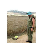 Un especialista en desactivar bombas de racimo examina un terreno