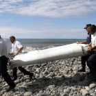 Cuatro policías trasladan los restos de un avión.
