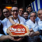 Pizzeros celebran el reconocimiento de la Unesco mientras posan con una pizza en Nápoles.