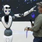 Un robot con tecnología 5G juguetea con uno de las asistentes. ANDREU DALMAU