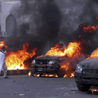 Coches policiales incendiados por unos manifestantes durante un acto de protesta en Karachi.