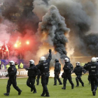 Antidisturbios saltan al césped del estadio del Hamburgo mientras en la grada se queman camisetas y banderas.