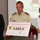 El alcalde, Arsenio García, observa la entrega del cheque del coronel a María Carracedo.