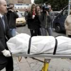 Un empleado de la funeraria traslada el cuerpo del joven