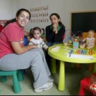 Una de las niñas de la nueva guardería de La Virgen, junto a sus dos tutoras
