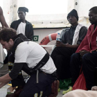 Un tripulante del ‘Aquarius’ atiende a uno de los inmigrantes cuyo destino es Valencia. KENNY KARPOV