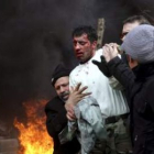 Varias personas ayudan a un policía herido durante las protestas en Irán.