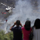Personal de tierra y un helicóptero trabajan en las labores de extinción de un incendio forestal registrado entre las localidades de Santovenia de la Valdoncina y Fresno del Camino
