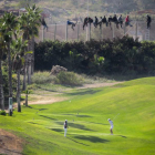Dos jugadoras en un campo de golf, a pocos metros de la valla de la frontera de Melilla.