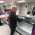 Una clienta realiza una gestión en una oficina bancaria en Tona (Osona).