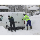 Un agente de la Guardia Civil ayuda al conductor de una furgoneta a salir de la nieve en un pueblo de la montaña leonesa