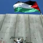 Un manifestante extranjero escribe consignas de protesta en el muro levantado por Israel