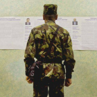 Un militar que apoyó la revuelta del Maidán repasa las candidaturas, en un colegio electoral de Kiev.